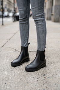 Black boots worn with gray jeans on a sidewalk