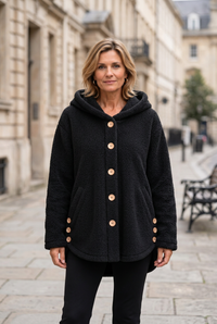 European woman wearing the black teddy coat on a sidewalk, with her whole face visible and the coat in focus