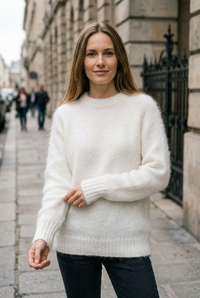 European woman wearing the white crew-neck sweater on a sidewalk